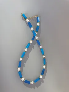 Close-up of beaded necklace with blue rectangle stones, pearls, and gold extender chain