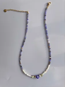Detail of colorful beads, white pearls and blue evil eye pendant on gold-plated chain