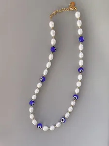 Close-up of beaded necklace with pearls, evil eye beads and 18k gold plated steel chain