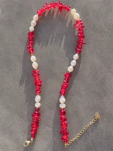 Dettaglio di perline rosse e perle irregolari con chiusura a moschettone dorata e catena