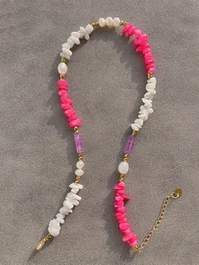 Dettaglio macro di una collana bohémien con pietre irregolari colorate e perle fini