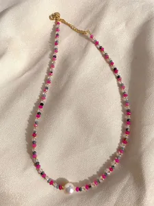 Detail of colorful faceted stone beads and a large white freshwater pearl on a gold chain