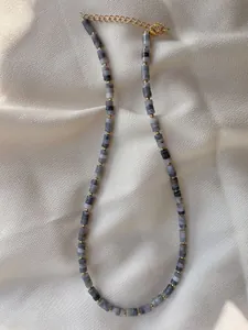 Detail of handmade stone beaded necklace with 18k gold plated clasp on satin fabric
