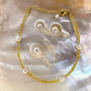 Detail of beaded bracelet with baroque pearls and yellow faceted stones on a shell