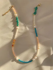 Close-up of handmade beaded necklace with turquoise and pearls on textured fabric