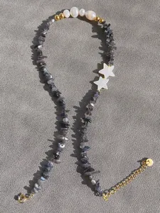 Dettaglio di collana bohemian con pietre grigio-blu e stelle in conchiglia bianca