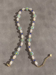 Vue détaillée de perles baroques et verre floral sur une chaîne en or 18 carats