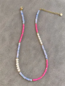 Detail of colorful beaded necklace with blue faceted gems and white baroque pearl