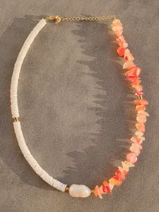 Dettaglio della collana di perline con pietre arancioni e perla barocca bianca