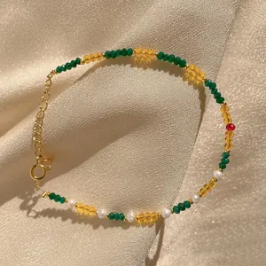 Detail of multi-color beads, freshwater pearls and 18K gold-plated chain on champagne silk