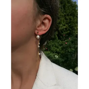 Elegant gold tassel earrings with freshwater pearls shown on a model in nature