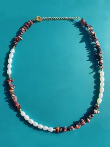 Dettaglio della collana boho con pietre rosse, perle e chiusura dorata regolabile