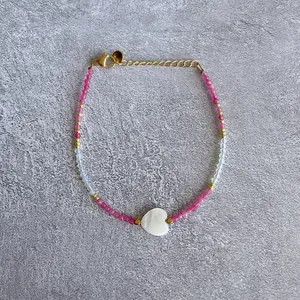 Close-up of beaded bracelet with pink natural stones and a white heart-shaped pendant