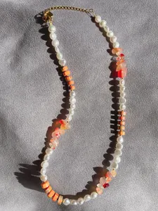 Dettaglio di perle bianche e pietre irregolari colorate sulla collana in stile boho