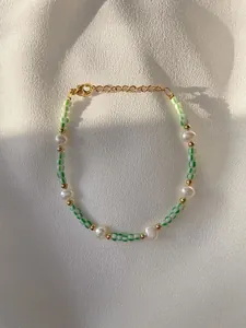 Detailed macro view of 18K gold-plated beaded bracelet with pearls and green beads