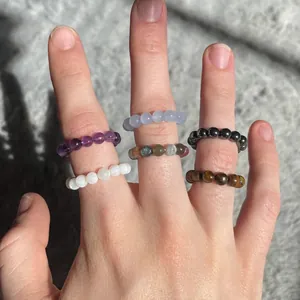 Detail of colorful handmade natural stone beaded stretch rings worn on model fingers