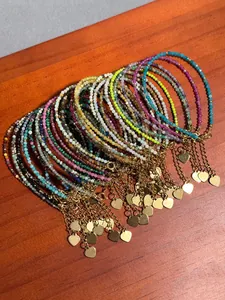 Gros plan de bracelets en pierres naturelles colorées avec breloques cœur doré sur bois