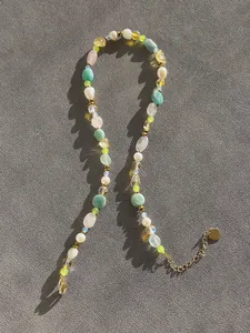 Dettaglio di perline colorate, perle d'acqua dolce e chiusura a cuore d'oro sulla collana