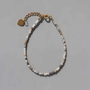 Détail d'un bracelet en perles de pierre naturelle avec pendentif cœur doré et chaînette