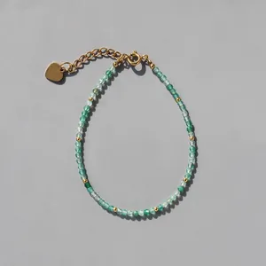 Détail d'un bracelet en perles vertes avec entretoises dorées et extension cœur doré