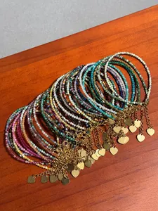 Detail of colorful stone beaded bracelets with 18k gold heart charms on a wooden table