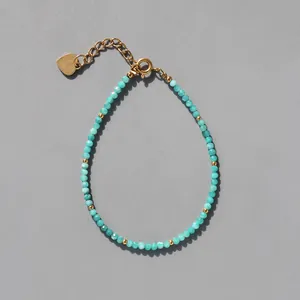 Détail d'un bracelet bohème en pierre naturelle avec breloque cœur doré et fermoir homard