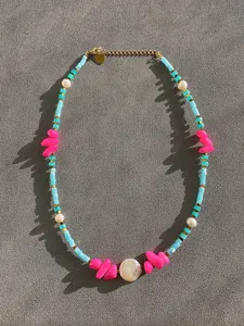 Dettaglio di perle colorate, perle barocche e chiusura a moschettone dorata sulla collana