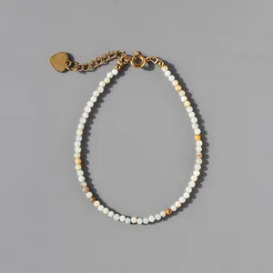 Detail of natural stone beaded bracelet with 18k gold heart pendant and lobster clasp