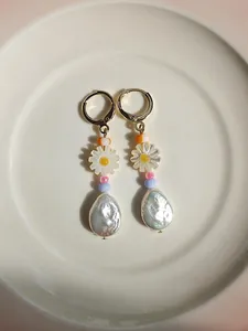 Dettaglio di orecchini fatti a mano in oro 18k con margherite e perle d'acqua dolce