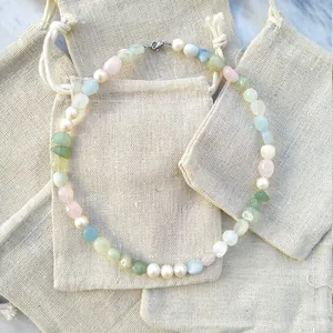 Handmade necklace with natural freshwater pearls and colorful gemstones on burlap bags