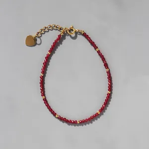 Détail du bracelet en perles facettées rouges avec pendentif cœur doré et fermoir
