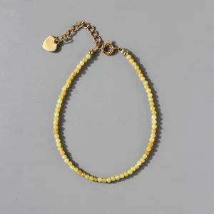 Macro detail of natural stone beaded bracelet with 18k gold heart pendant and extension chain