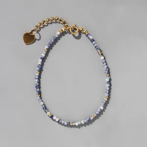 Détail de perles de pierre naturelle bleue facettée avec breloque cœur et fermoir doré