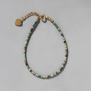 Détail de perles en pierre colorées avec breloque cœur doré et fermoir mousqueton