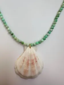 Detailed macro view of a light green gemstone beaded necklace with a natural seashell charm