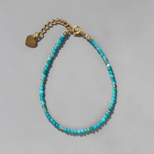 Détail des perles en pierre naturelle bleue facettée et du pendentif cœur doré du bracelet