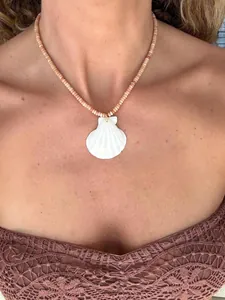Close-up of a bohemian shell necklace with natural stone beads on a female model