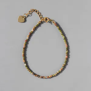 Close-up of multicolored natural stone beads with gold heart pendant and lobster clasp
