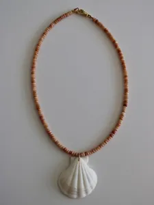 Flat lay of handmade peach beaded necklace featuring a white seashell pendant and gold clasp