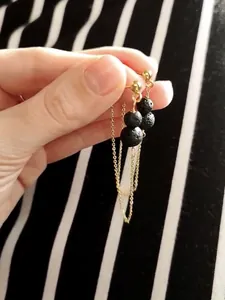 Detail of 18k gold plated titanium chain earrings with natural black lava stone beads
