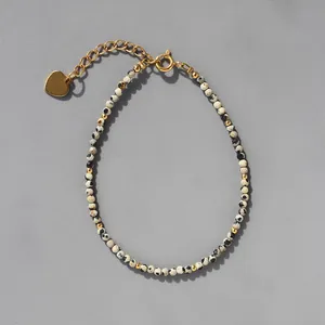 Détail du bracelet en pierres avec pendentif cœur doré et chaîne de réglage