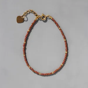 Détail du bracelet en perles avec breloque cœur dorée et fermoir mousqueton réglable