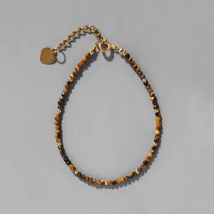 Détail macro de perles en œil de tigre avec pendentif cœur doré et chaîne ajustable