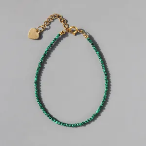 Detail of natural green stone beaded bracelet with 18k gold plated heart charm and clasp