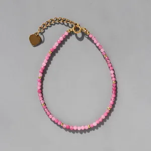 Gros plan du bracelet en perles de pierre rose avec pendentif coeur doré et fermoir mousqueton