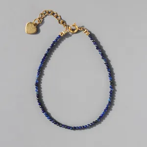 Macro view of blue lapis stone beaded bracelet with 18k gold plated heart charm detail