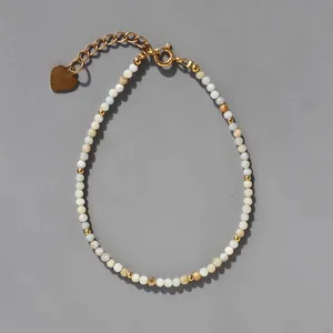 Détail de perles en pierre naturelle avec breloque cœur doré et chaîne d'extension