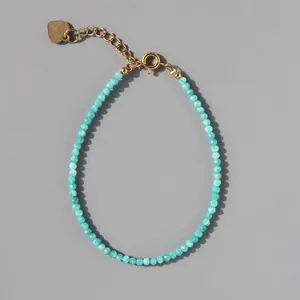 Close-up of sky blue faceted beads bracelet with gold lobster clasp and heart pendant