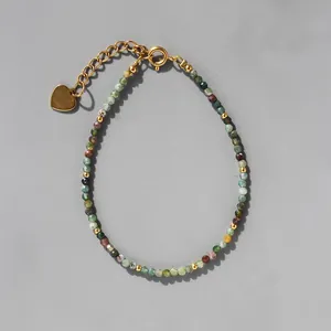 Détail d'un bracelet en perles de pierre naturelle avec breloque cœur doré et chaînette