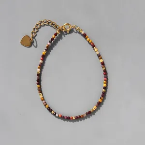 Détail de perles en pierre naturelle colorée avec pendentif coeur doré sur la chaîne